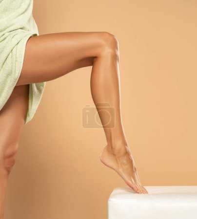 Téléchargez les photos : Woman's leg with smooth skin after depilation on beige studio background. - en image libre de droit