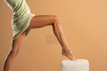 Téléchargez les photos : Woman's leg with smooth skin after depilation on beige studio background. - en image libre de droit
