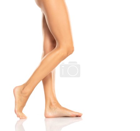 Téléchargez les photos : Side profile view of a beautiful women's feet and legs on white studio background - en image libre de droit