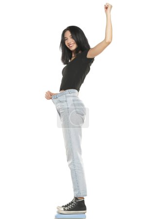 Photo for Weight loss happy woman standing on a scale, isolated on a white studio background. Slim Body - Royalty Free Image