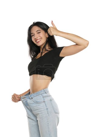Foto de Weight loss happy woman showing thumbs up, isolated on a white studio background. Slim Body - Imagen libre de derechos