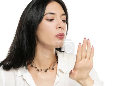 Téléchargez les photos : Une femme souffle son vernis frais sur un fond de studio blanc - en image libre de droit