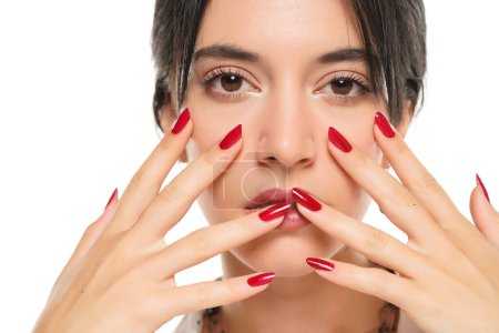 Foto de Mujer muestra su esmalte de uñas rojo sobre un fondo de estudio blanco. de cerca - Imagen libre de derechos
