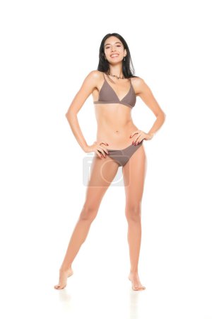 Foto de Joven morena sonriente en bikini posando sobre un fondo de estudio blanco. - Imagen libre de derechos