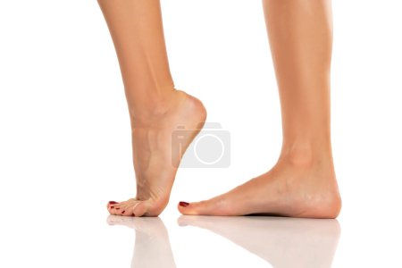 Foto de Side view of a beautifully cared female feet on a white studio background. - Imagen libre de derechos
