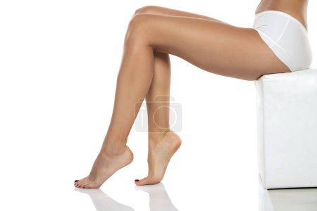 Foto de Side view of beautifully cared women's legs and feet on white studio background. - Imagen libre de derechos