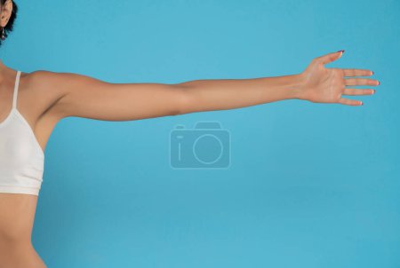 Photo for Young woman's stretched arm and palm. Isolated on blue studio background. - Royalty Free Image
