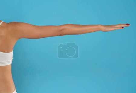 Téléchargez les photos : Le bras tendu et la paume de la jeune femme. Isolé sur fond bleu studio. - en image libre de droit