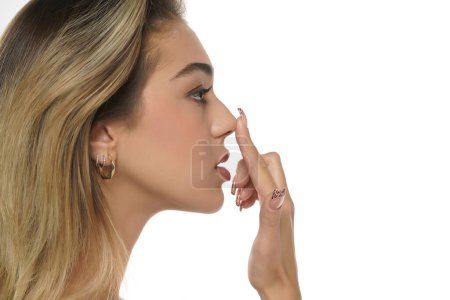 Photo for Young woman touches her nose with her finger on a white studio background - Royalty Free Image