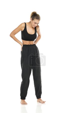 Photo for A young sporty woman with pain in her waist on a white studio background - Royalty Free Image