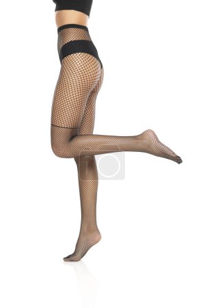 Photo for Young female legs in black fishnet stockings on white studio background - Royalty Free Image