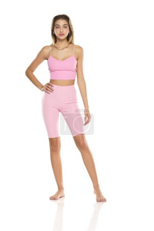 Photo for A young barefeet woman in pink short leggings and top posing on a white studio background - Royalty Free Image