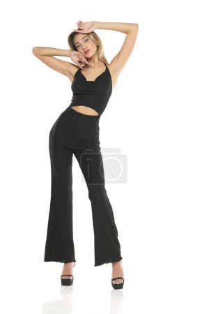 Foto de Una mujer joven en pantalones anchos negros y sujetador posando sobre un fondo de estudio blanco - Imagen libre de derechos