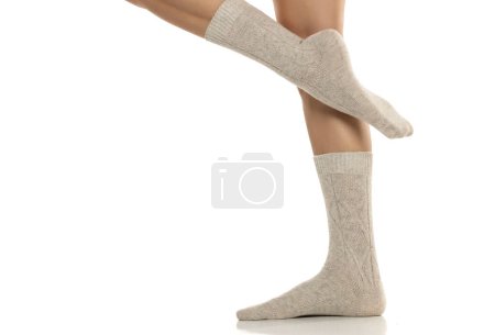 Téléchargez les photos : Gros plan des jambes féminines en laine grise chaussettes d'hiver sur fond de studio blanc - en image libre de droit