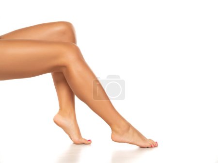 Photo for Beautiful smooth woman waxing legs and feet isolated on a white studio background - Royalty Free Image