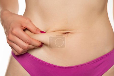 Foto de Mujer pellizcando su vientre sobre fondo blanco del estudio - Imagen libre de derechos