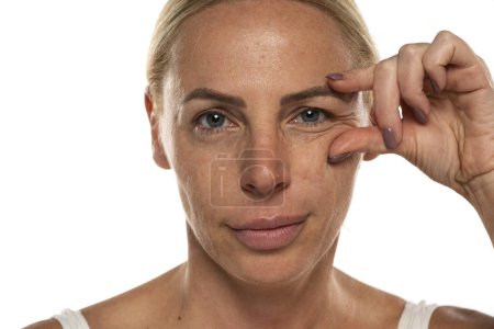 Foto de Retrato de una mujer mayor sin maquillaje mostrando sus arrugas en un fondo de estudio blanco - Imagen libre de derechos