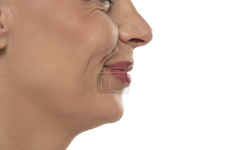 Photo for Closeup profile of a middle aged woman's face, smile, mouth, nose and cheek on a white studio background - Royalty Free Image