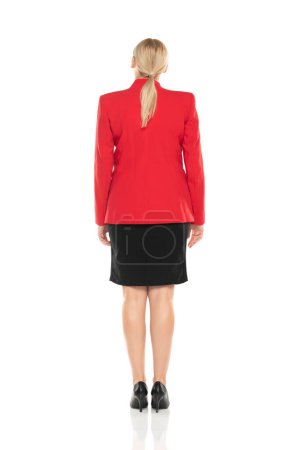 Photo for Middle aged senior business woman in red jacket and black skirt posing on white studio background. Back, rear view. - Royalty Free Image