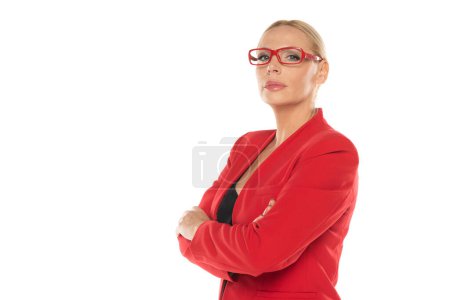 Foto de Mujer de mediana edad de negocios senior en chaqueta roja con brazos cruzados sobre fondo de estudio blanco - Imagen libre de derechos