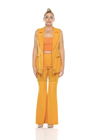 Photo for Middle aged senior woman in yellow sleevless jacket and trousers posing on a white studio background - Royalty Free Image