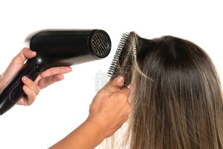 Téléchargez les photos : Vue arrière d'un coiffeur séchant les cheveux d'une femme en studio sur fond blanc - en image libre de droit