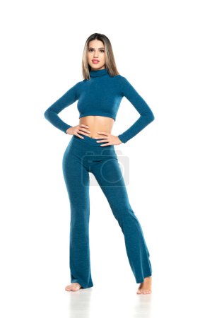 Foto de Joven mujer sonriente desnuda moderna en pantalones azules y blusa posando sobre fondo blanco del estudio. vista frontal - Imagen libre de derechos