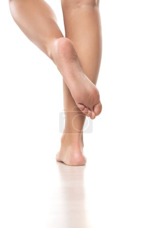 Téléchargez les photos : Vue arrière d'une femme joliment soignée pieds nus sur un fond de studio blanc. - en image libre de droit