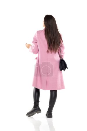 Téléchargez les photos : Vue arrière d'une jeune femme en manteau d'hiver, et bottes noires posant sur un fond blanc - en image libre de droit