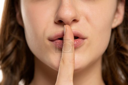 Téléchargez les photos : Gros plan d'une femme lèvres avec un doigt demandant le silence - en image libre de droit