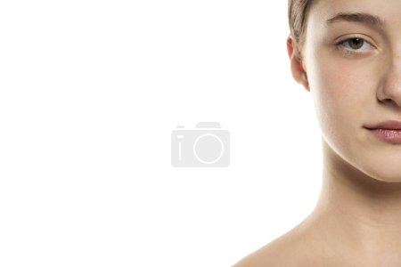 Foto de Mitad retrato de una hermosa mujer joven con el pelo atado y sin maquillaje en un fondo de estudio blanco. - Imagen libre de derechos
