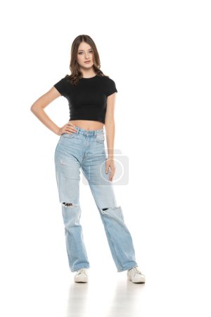 Photo for Young female model wearing ripped jeans and black shirt posing on a white studio background. Front view - Royalty Free Image