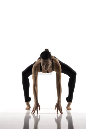 Téléchargez les photos : Yoga, sport, entraînement et concept de style de vie - Jeune femme faisant de l'exercice de yoga. Portrait de jeune belle femme en tenue de sport noire pratiquant le yoga. - en image libre de droit