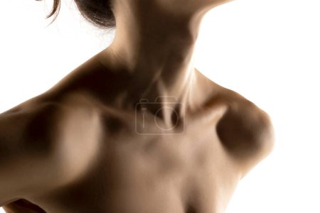 Téléchargez les photos : Le gros plan du cou et des épaules d'une jeune femme à l'ombre sur fond de studio blanc - en image libre de droit