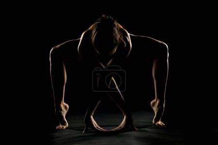 Téléchargez les photos : Silhouette d'art d'une jeune femme faisant de l'exercice de yoga. pose de yoga sur fond noir studio. - en image libre de droit