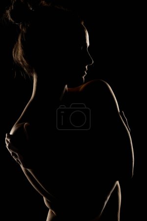 Téléchargez les photos : Sensuelle silhouette portrait de belle femme en contre-jour sur fond de studio noir - en image libre de droit