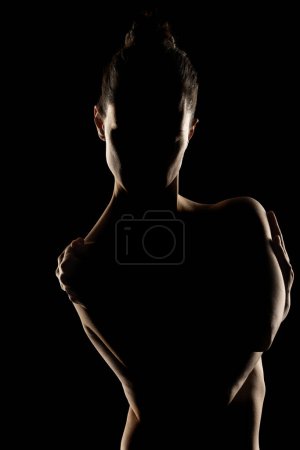 Téléchargez les photos : Sensuelle silhouette portrait de belle femme en contre-jour sur fond de studio noir - en image libre de droit