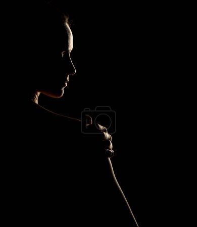Foto de Sensual silueta de retrato de mujer hermosa en contraluz sobre un fondo de estudio negro - Imagen libre de derechos