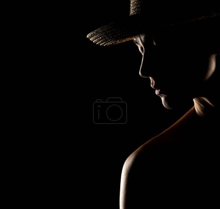 Foto de Sensual silueta de retrato de mujer hermosa con un sombrero en contraluz sobre un fondo de estudio negro - Imagen libre de derechos