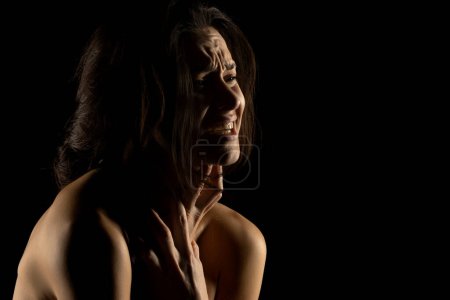 Téléchargez les photos : Silhouette de jeune femme pleure malheureuse sur fond de studio noir - en image libre de droit