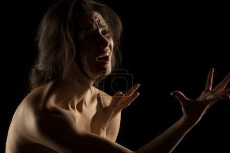 Téléchargez les photos : Silhouette de jeune femme pleure malheureuse sur fond de studio noir - en image libre de droit