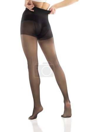 Foto de La mujer se pone medias negras en sus hermosas piernas largas, aisladas sobre fondo blanco del estudio - Imagen libre de derechos