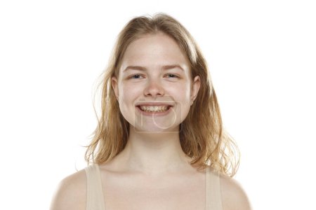 Téléchargez les photos : Portrait de jeune belle femme blonde souriante sans maquillage sur fond de studio blanc - en image libre de droit