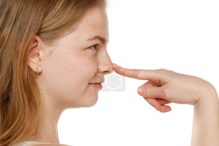 Téléchargez les photos : Profil de jeune femme qui se touche le nez sur fond de studio blanc - en image libre de droit