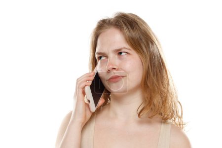 Photo for Portrait of young beautiful nervous blonde woman with no makeup talk on the mobile phone on white studio background - Royalty Free Image