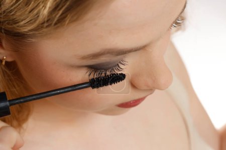 closeup of a young woman applying mascara on a white studio background-stock-photo