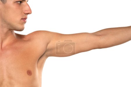 Foto de Imagen recortada de un hombre musculoso con el brazo extendido. modelo de moda joven en topless con su mano en el aire. Aislado sobre un fondo de estudio blanco - Imagen libre de derechos