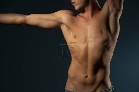 Téléchargez les photos : Le torse d'un jeune athlète. concept : le corps masculin après l'exercice et l'alimentation. santé des hommes : seins rasés sur fond de studio sombre - en image libre de droit