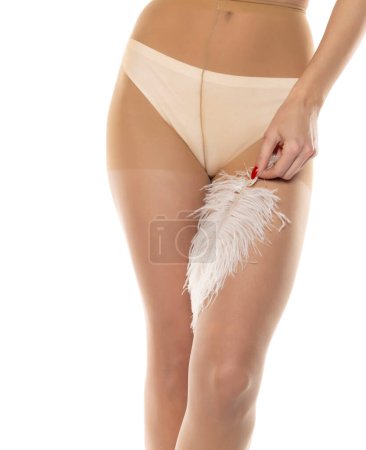 Foto de Mujer con mallas, toques con plumas, aislado en blanco, primer plano de las piernas sobre un fondo de estudio blanco. Vista frontal - Imagen libre de derechos