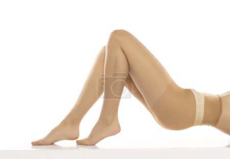 Photo for Woman wearing tights lying isolated on white, closeup of legs on a white studio background. Profile, side view - Royalty Free Image